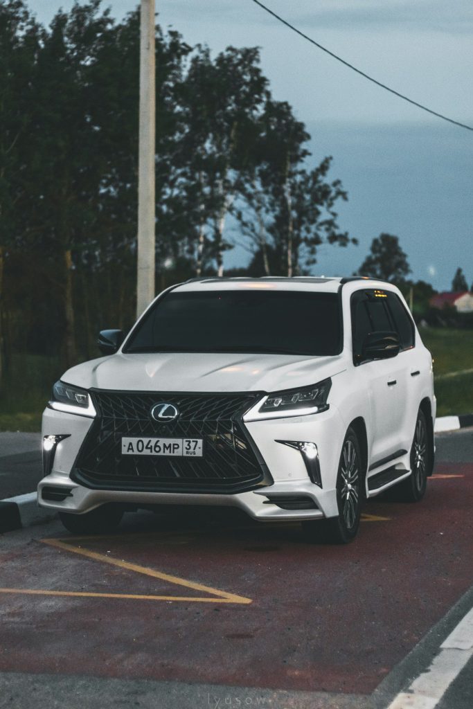 Một chiếc Lexus LX màu trắng với lưới tản nhiệt hình con suốt lớn đỗ bên đường lúc chạng vạng
