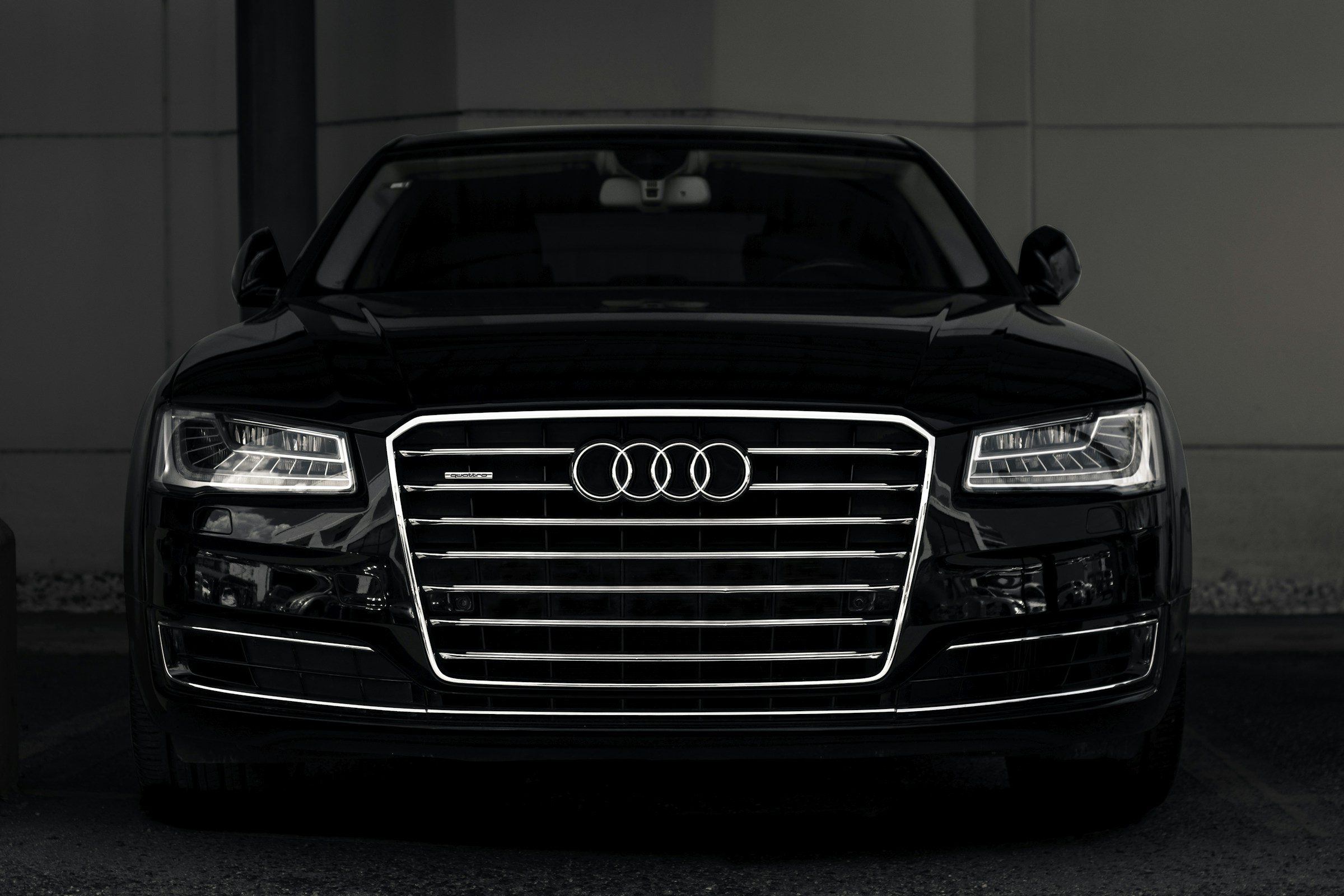 Đầu xe Audi A8 màu đen với lưới tản nhiệt lớn, nền tối